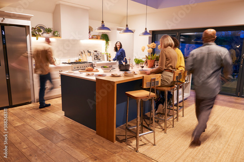 Canvas Print Motion Blur Shot Of Mature Friends Meeting At Home For Evening Dinner Party