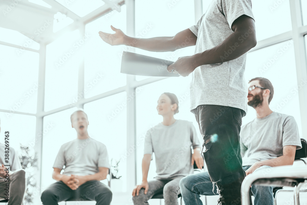 background image of a speaker reading a report to a group of students. background image of a speaker reading a report to a group of students.