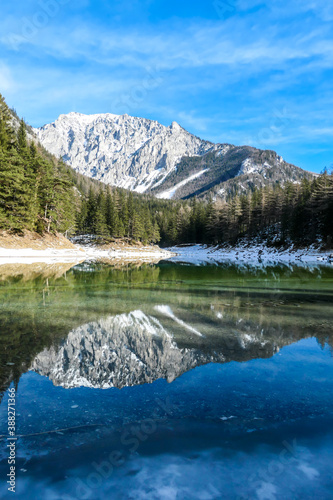 Winter landscape of Austrian Alps with Green Lake in the middle. Powder snow covering the mountains and ground. Soft reflections of Alps in calm lake s water. Winter wonderland. Serenity and calmness
