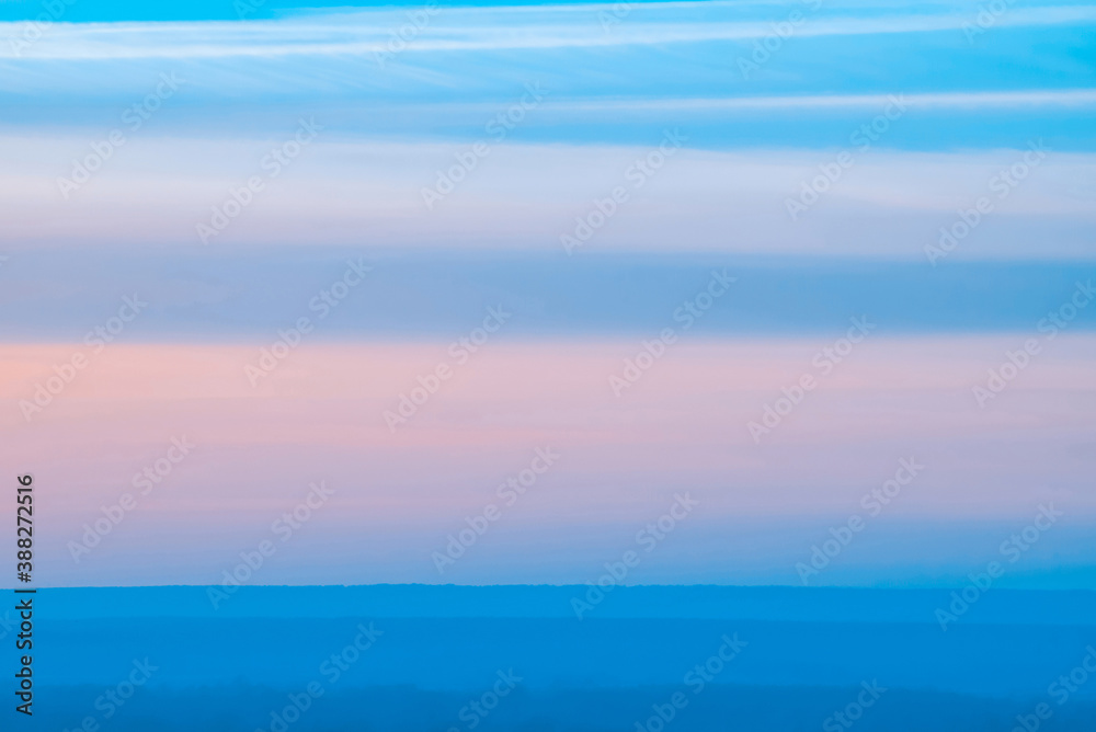 Varicolored striped surreal sky with shades of blue, cyan, pink colors with land. Horizontal lines of smooth clouds. Atmospheric background image of tender sky.