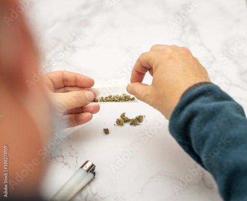 View from above of a man preparing a Marijuana and hashish cigar with roller paper