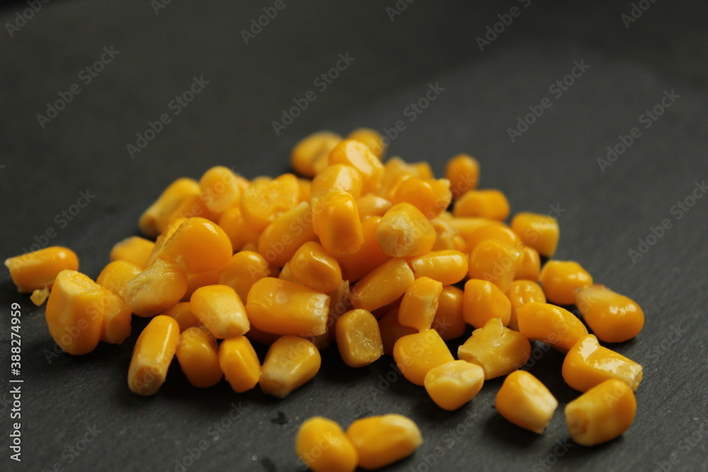Fototapeta premium food background sweet sugar yellow corn lying in a pile on a rock dark gray background copy space side view