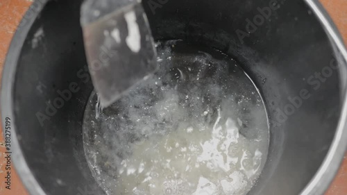 knead gypsum plaster in a black bucket, professional movements