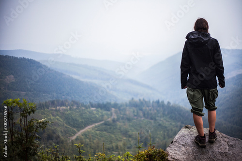 Fototapeta Naklejka Na Ścianę i Meble -  A person standing on a stone in the mountains overlooking the valley.