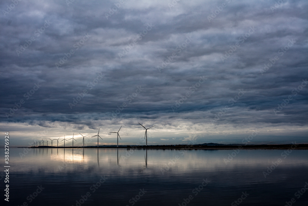 View from the water's perspective of the windmills on the shore.