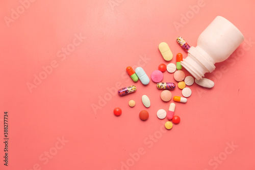 top view of pills and capsule spilling on pink background 