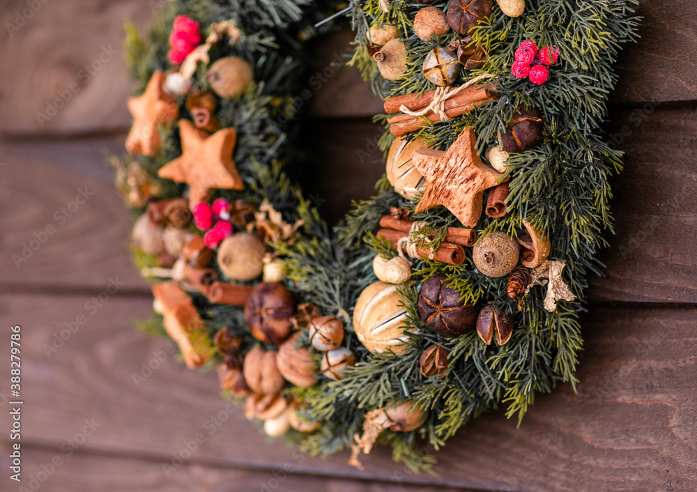 Traditional Christmas wreath made of fir branches, decorated with ginger cookies, cinnamon, nuts, berries, bells and a beautiful bow