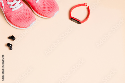Fittnes sport composition with pink sneakers, smart bracelet on pink background.