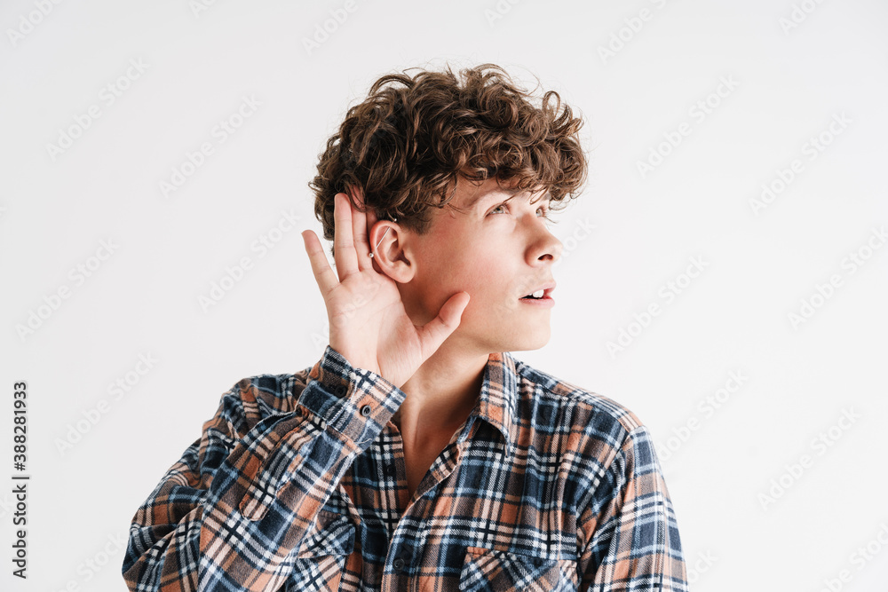 Focused curly guy with earring overhearing and looking aside Focused curly guy with earring overhearing and looking aside