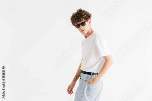 Young curly caucasian guy in sunglasses looking at camera