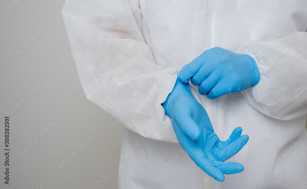 Close up A portrait of virologist put on PPE suit checking blue glove on his hand isolated on white background. Personal Protective Equipment Concept. Close up A portrait of virologist put on PPE suit checking blue glove on his hand isolated on white background. Personal Protective Equipment Concept.