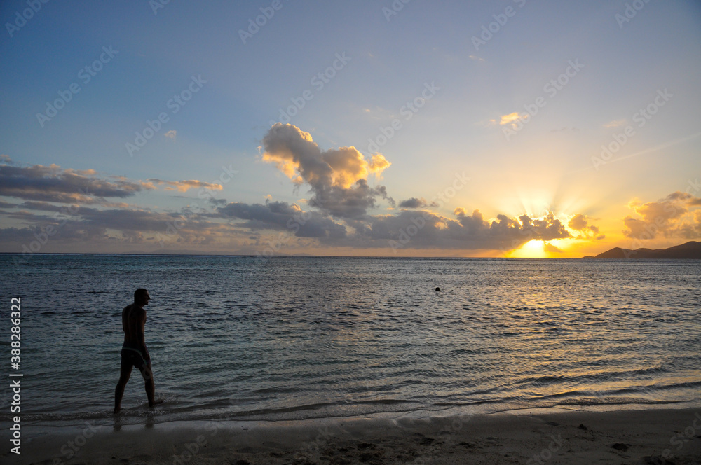 Silhouette of man with the arms a cross on beach at sunset