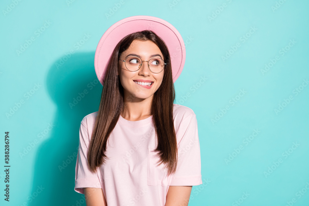 Photo of shy pretty charming girl look copyspace bite teeth lips wear clothes isolated over teal color background Photo of shy pretty charming girl look copyspace bite teeth lips wear clothes isolated over teal color background