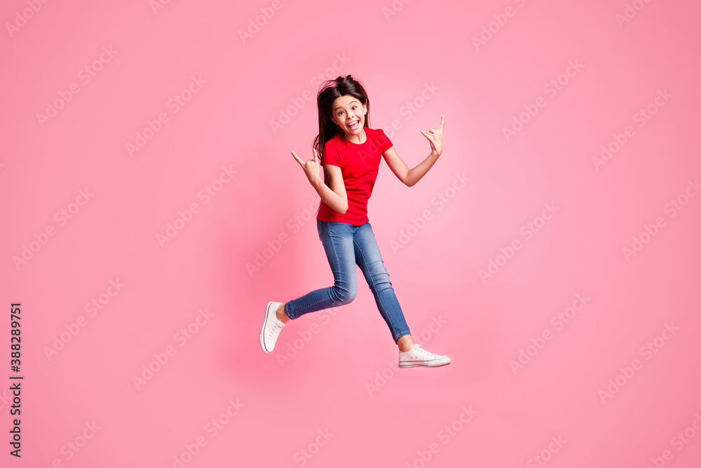 Full size photo of crazy kid girl jump show horned symbol wear red t-shirt denim isolated over pastel color background Full size photo of crazy kid girl jump show horned symbol wear red t-shirt denim isolated over pastel color background