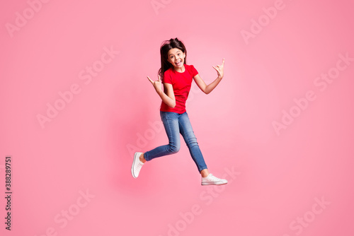 Full size photo of crazy kid girl jump show horned symbol wear red t-shirt denim isolated over pastel color background