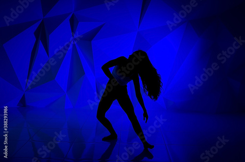 Woman dancing on the background of a beautiful multicolored wall. Sexy slim lonely girl with long black hair. female holds her head. bright colorful geometry background.