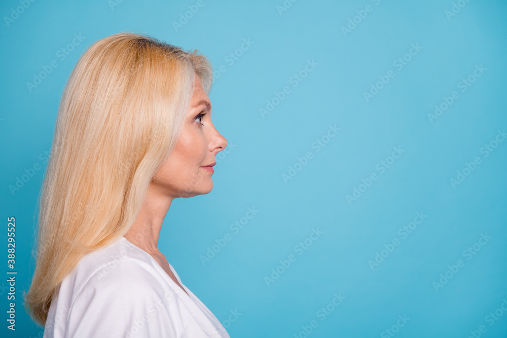 Photo of attractive aged lady woman charming appearance look empty space wear t-shirt isolated blue color background Photo of attractive aged lady woman charming appearance look empty space wear t-shirt isolated blue color background