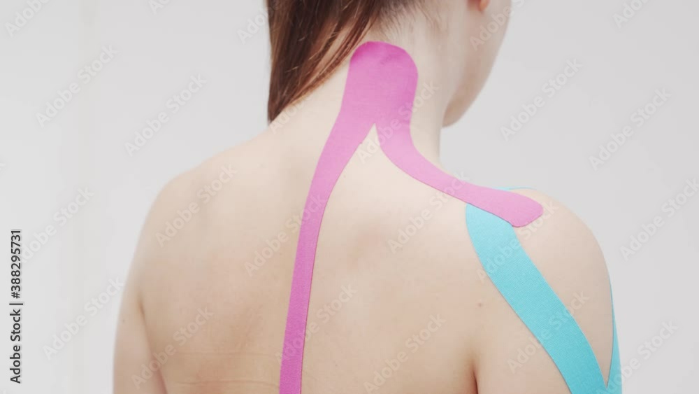 Therapist is applying kinesio tape to female body. Physiotherapy and kinesiology concepts.