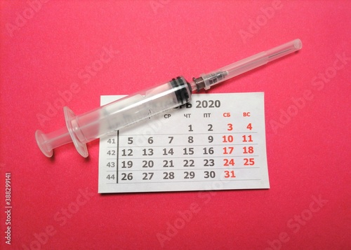calendar and syringe on pink background