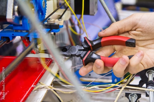 Male hand is configuring settings using nose pliers.