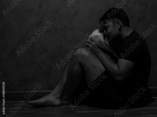 Asian man are sitting on the floor in house and looked sad. Black and white images of the man with cat are suffering from depression.