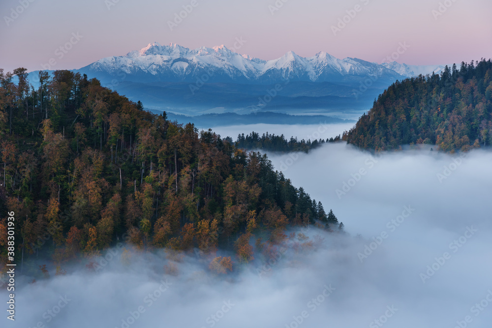 Beautiful morning mountain scenery with fogs and snow-capped peaks