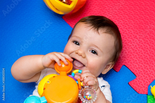 Funny baby playing on colorful eva rubber floor. Toddler having fun indoor his home. Top view. Copy space.