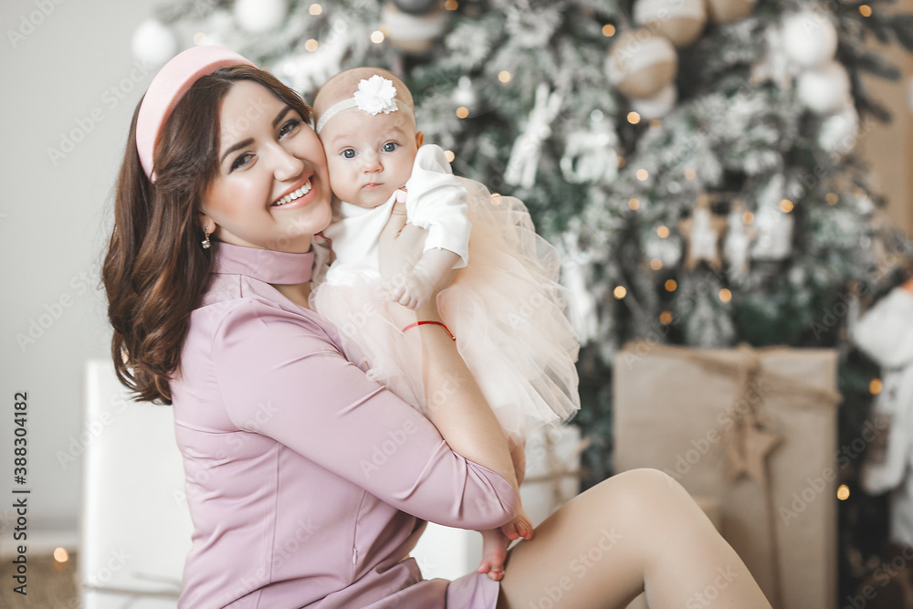 Fototapeta premium Young mother and her little baby daughter on christmas background