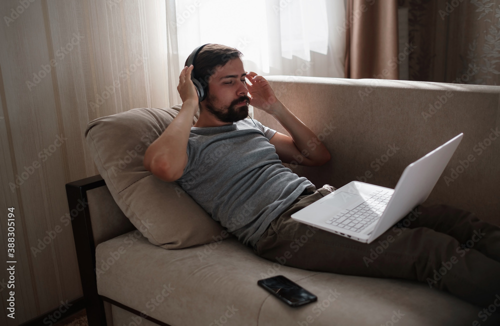 Man on sofa with headphones and notebook at home Man on sofa with headphones and notebook at home