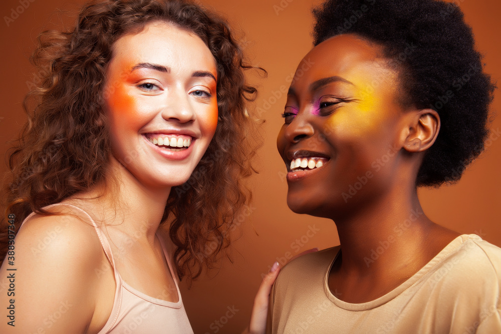 two pretty girls african and caucasian blond posing cheerful together on brown background, ethnicity diverse lifestyle people concept two pretty girls african and caucasian blond posing cheerful together on brown background, ethnicity diverse lifestyle people concept