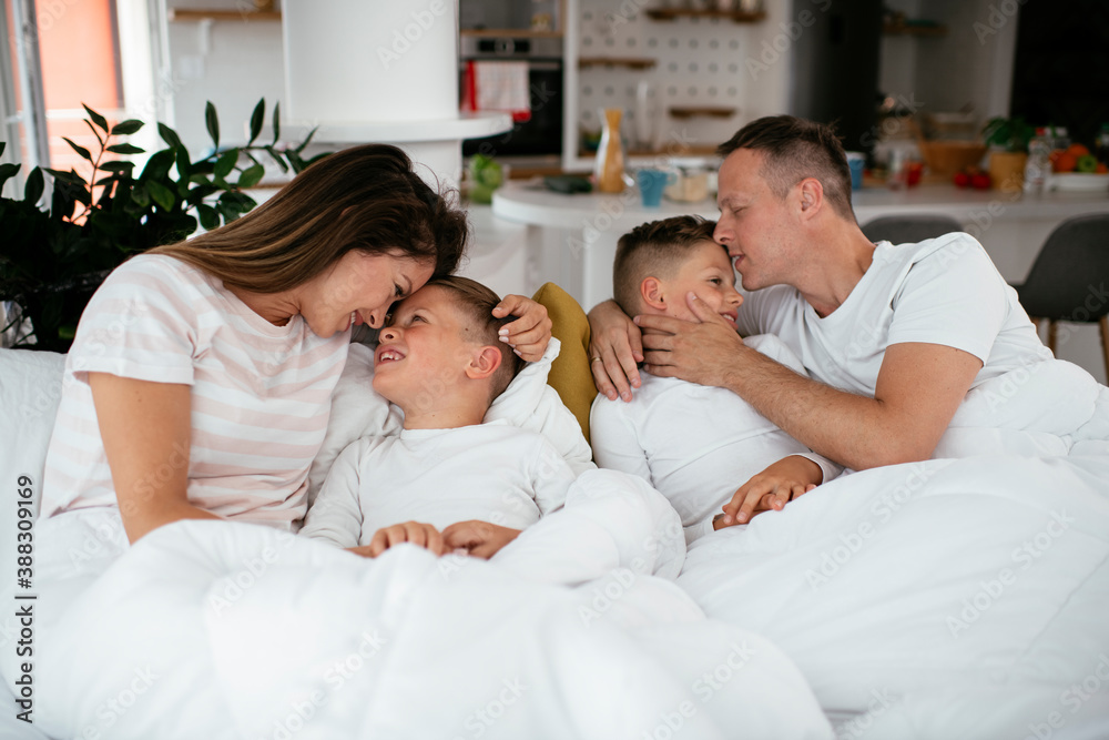 Young family enjoying in bed. Happy parents with sons relaxing in bed. Young family enjoying in bed. Happy parents with sons relaxing in bed.