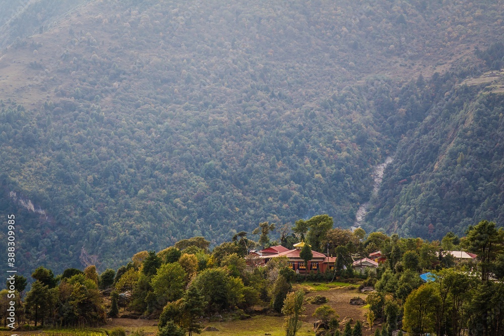 Beautiful biddhism monastery surrounded with green trees and amazing high mountains on the background. Nepalese Himalaya.