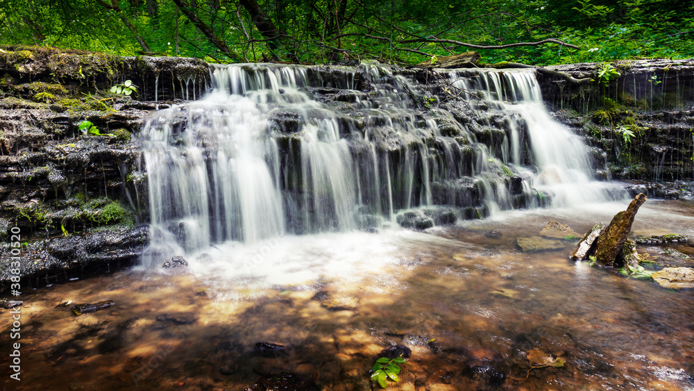 Small waterfall in soft light on a sunny day