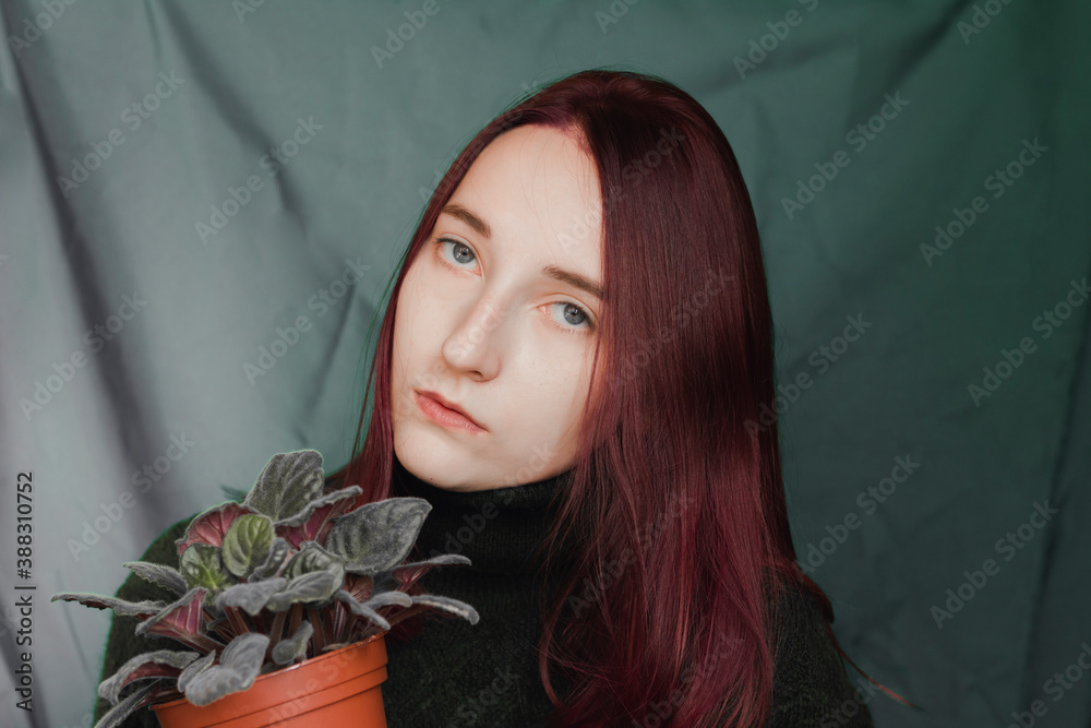 Naklejka premium Portrait of a beautiful girl with a violet. The girl has purple hair and a violet.