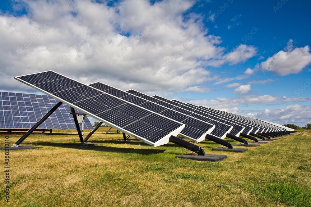 Many solar panels on a green field against blue sky in a sunny day. Alternative sources of energy. Many solar panels on a green field against blue sky in a sunny day. Alternative sources of energy.