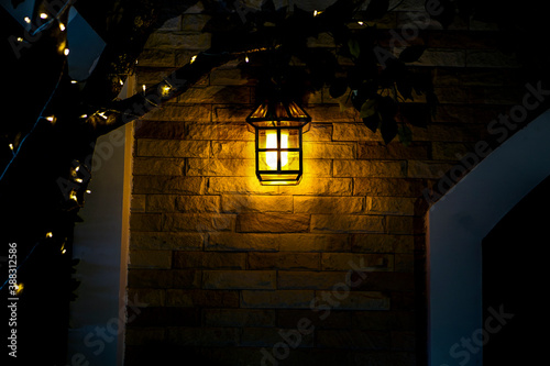 The lamp shines against the brick wall.
