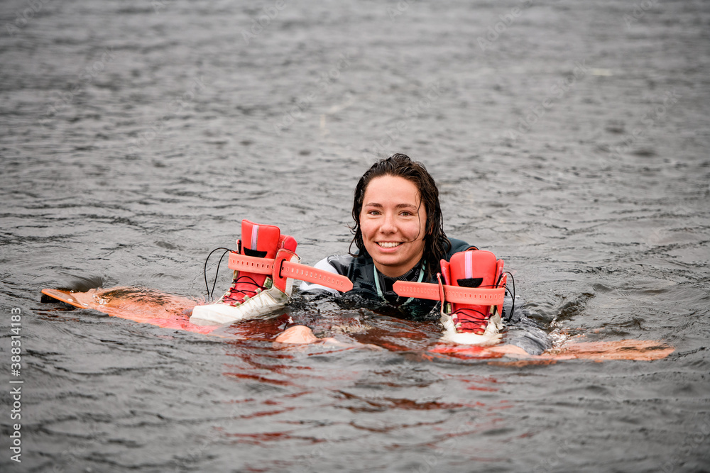 Obraz premium happy young woman swims in the water in vest with bright wakeboarding board
