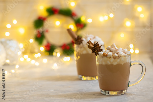 Spiced christmas drink latte with marshmallows on the celebration table with cinnamon and anise decoration