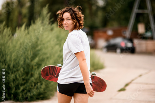 happy woman in white t-shirt with her head turned back and skateboard in her hand