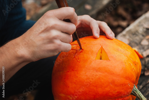 guy carves Jack o lantern out of pumpkin close up,