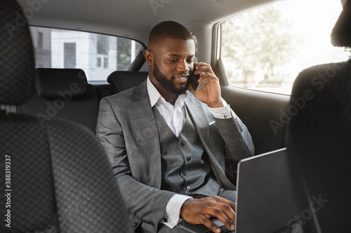 Картината върху платно Happy black businessman talking on mobile phone in car