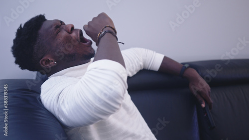 Photos anxious black man yawning on the couch. High quality photo