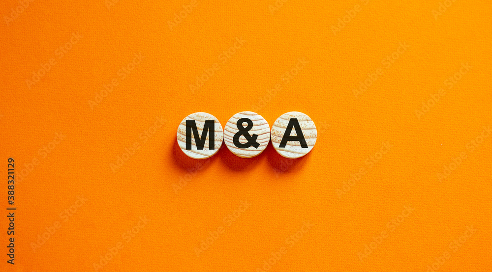 Concept word 'M and A' on wooden circles on a beautiful orange background. Business concept. Copy space. Concept word 'M and A' on wooden circles on a beautiful orange background. Business concept. Copy space.