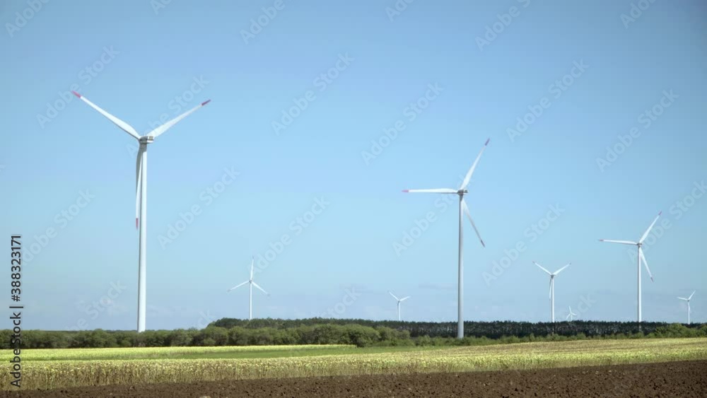Wind energy turbines in a field of sunflowers against a clear blue sky. Renewable energy sources, environmentally friendly energy Wind energy turbines in a field of sunflowers against a clear blue sky. Renewable energy sources, environmentally friendly energy