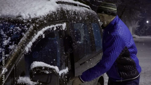 man gets out of the car in winter,happy man arrived at night by car in winter
