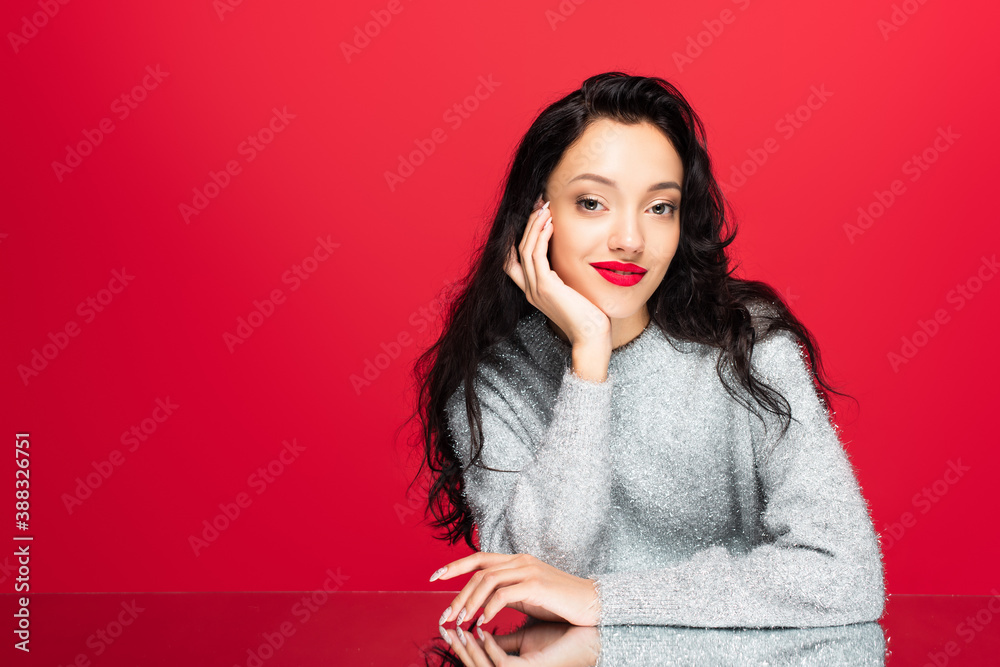 young pleased woman in sweater looking at camera isolated on red young pleased woman in sweater looking at camera isolated on red