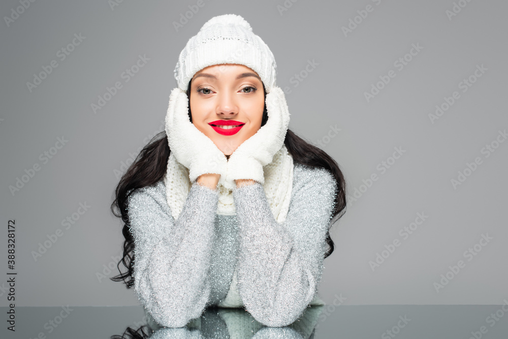 joyful and brunette woman in winter outfit looking at camera isolated on grey joyful and brunette woman in winter outfit looking at camera isolated on grey