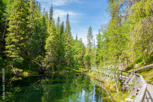 Fototapeta Naklejka Na Ścianę i Meble -  View of The Pyha-Luosto National Park in summer, stones, trees, wooden walkway and natural pond, Lapland, Finland