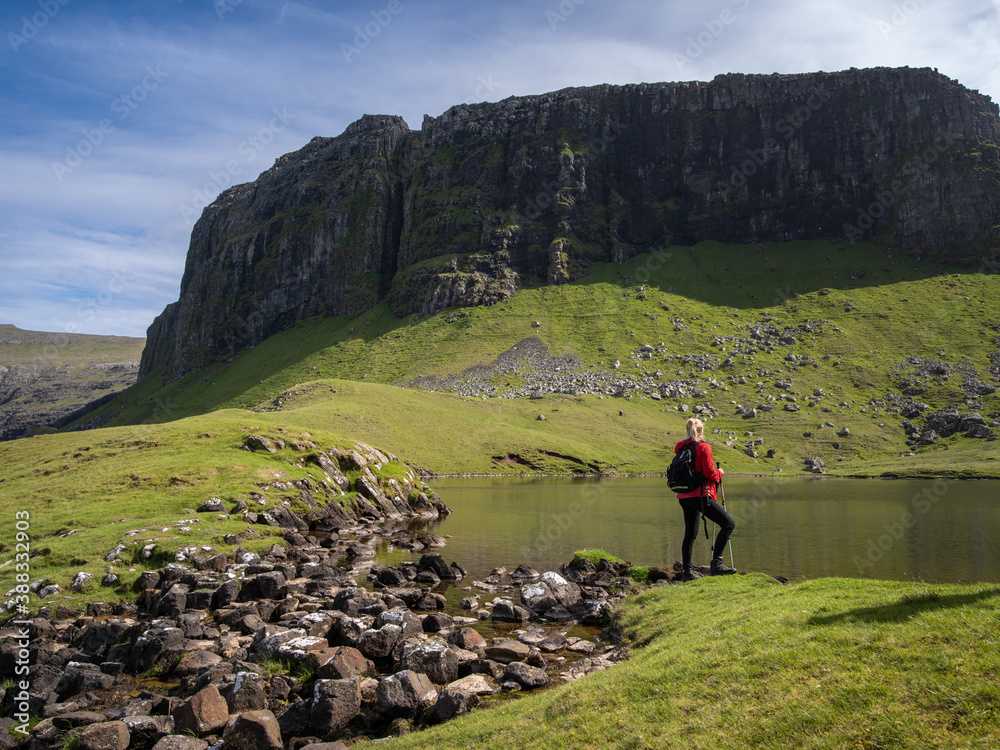 Hiker in red jacket at Hvannhagi and Lake Hvannavatn, Suðuroy, Faroe Islands.