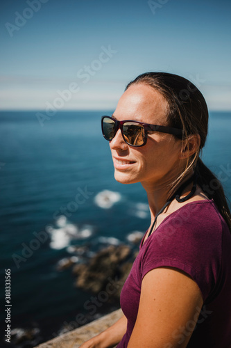 White woman with sunglases enjoying views from a cliff in atlantic ocean. © daviles